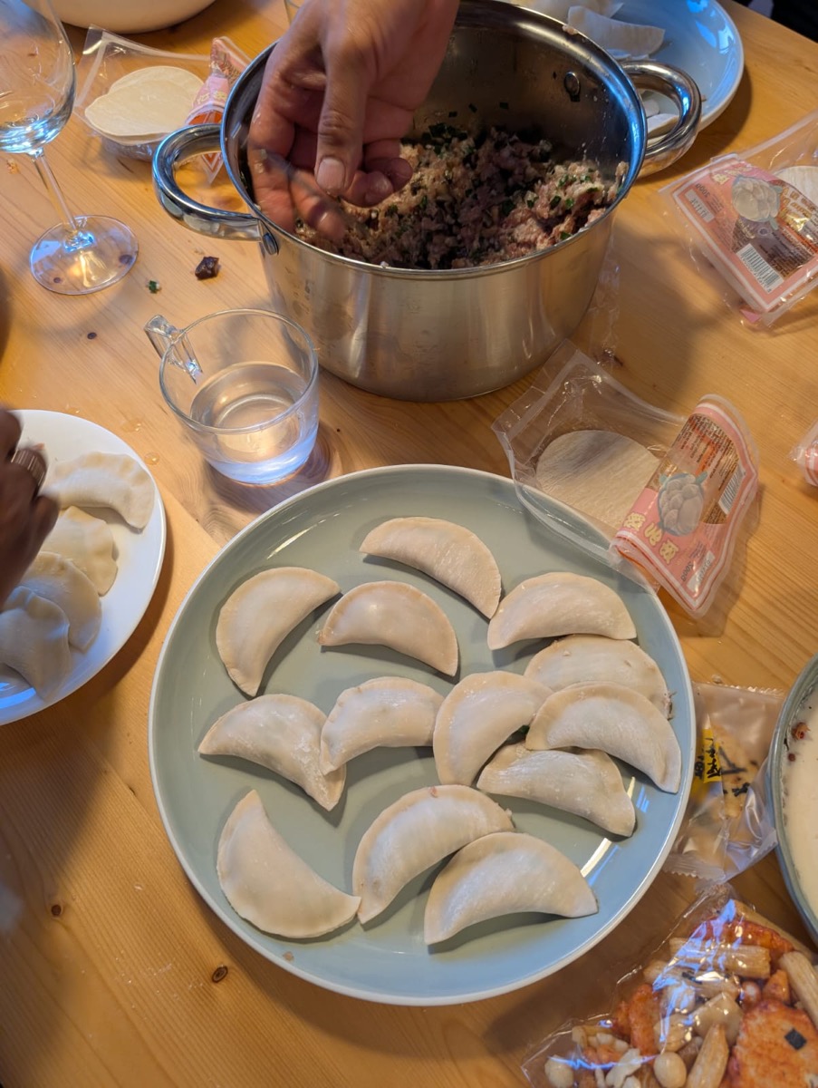 Guests folding dumplings by hand at the Dumplings & AI collaborative dinner in Lisbon